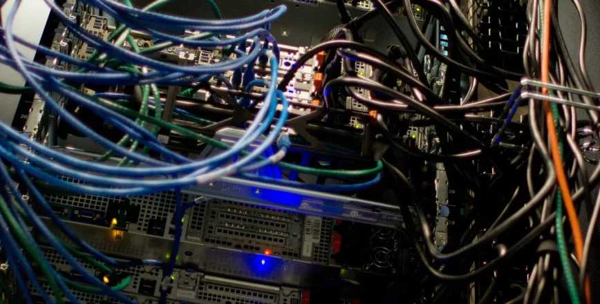 Vue rapprochée d'un rack de serveurs rempli de câbles et de matériel informatique.