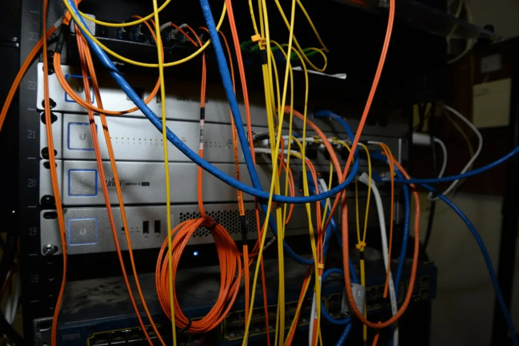 Un rack de serveurs est encombré de nombreux câbles de différentes couleurs.