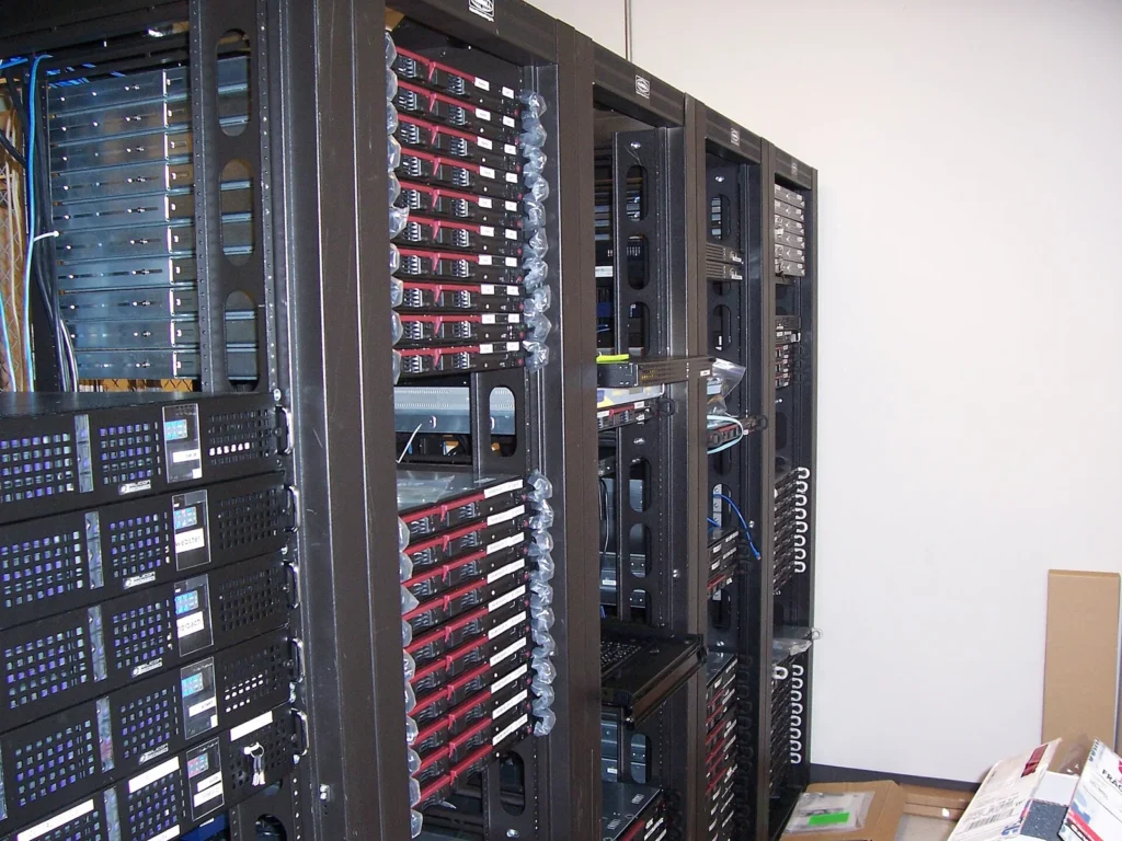 Une rangée de serveurs informatiques en rack est visible dans une salle de serveurs.