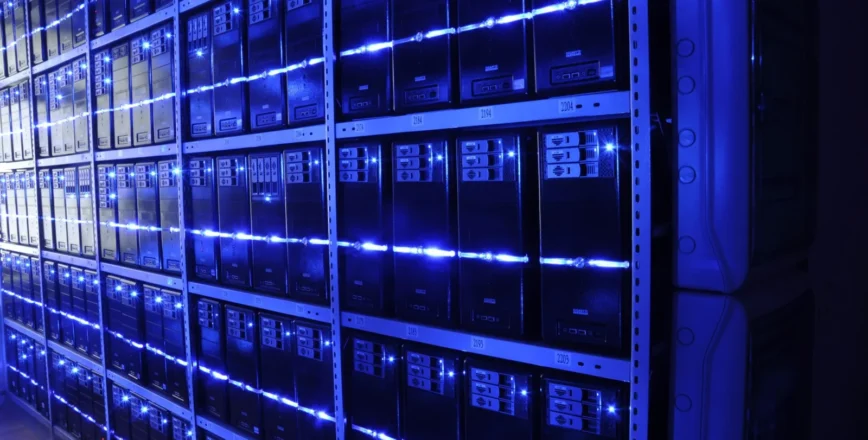 Une rangée de serveurs informatiques dans un centre de données, illuminés par des lumières bleues.