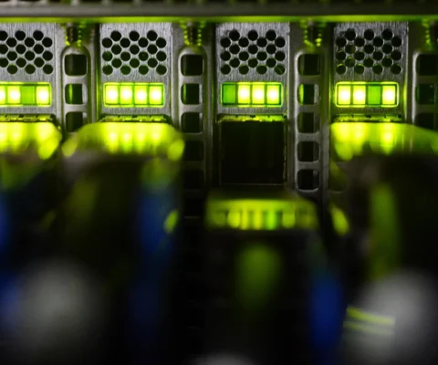 Un gros plan sur des serveurs informatiques illuminés de lumières vertes, suggérant un environnement de calcul haute performance.