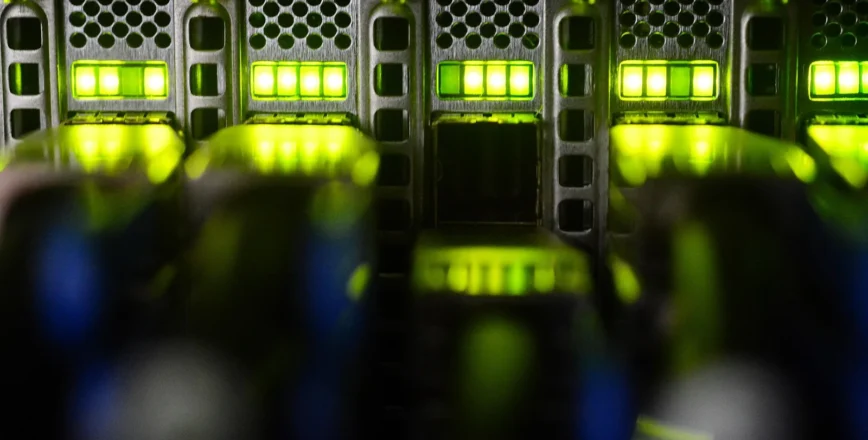 Un gros plan sur des serveurs informatiques illuminés de lumières vertes, suggérant un environnement de calcul haute performance.